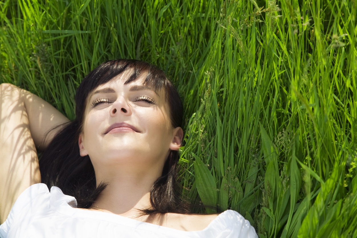 Why does fresh air make you tired? Woman asleep on grass outside.