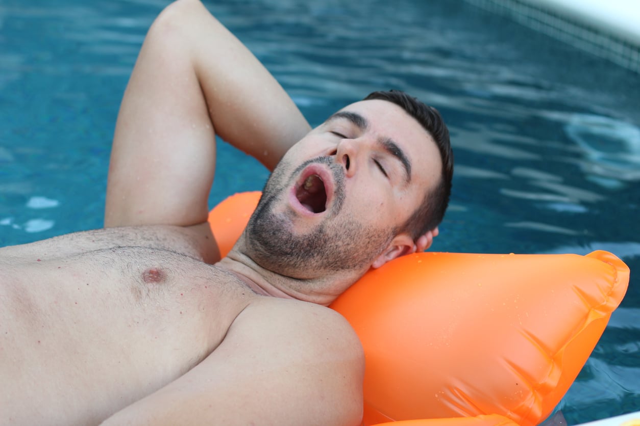 Why does going to the pool make you tired? Man yawning in swimming pool.